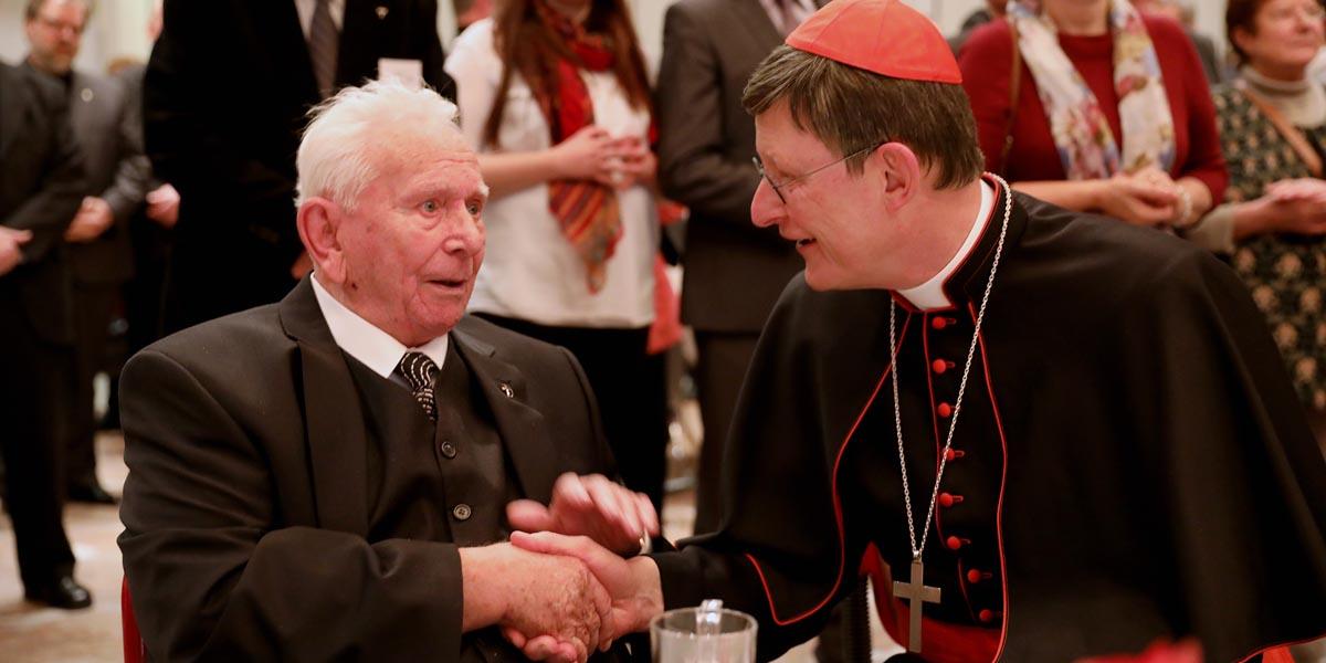 Kardinal Woelki begrüßt Diakon Wolfgang Speicher. Er ist der einzige noch lebende Ständige Diakon aus dem ersten Weihejahrgang im Erzbistum Köln 1968