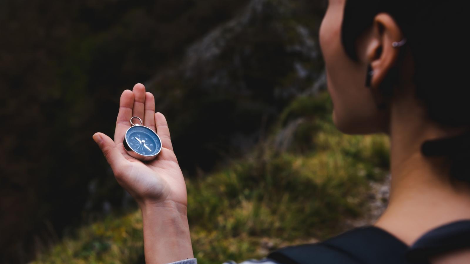 Orientierung (Symbolbild) young girl holding a compass in hand, ready to travel, keep calm. Tourism, traveling, hiking and healthy lifestyle concept.