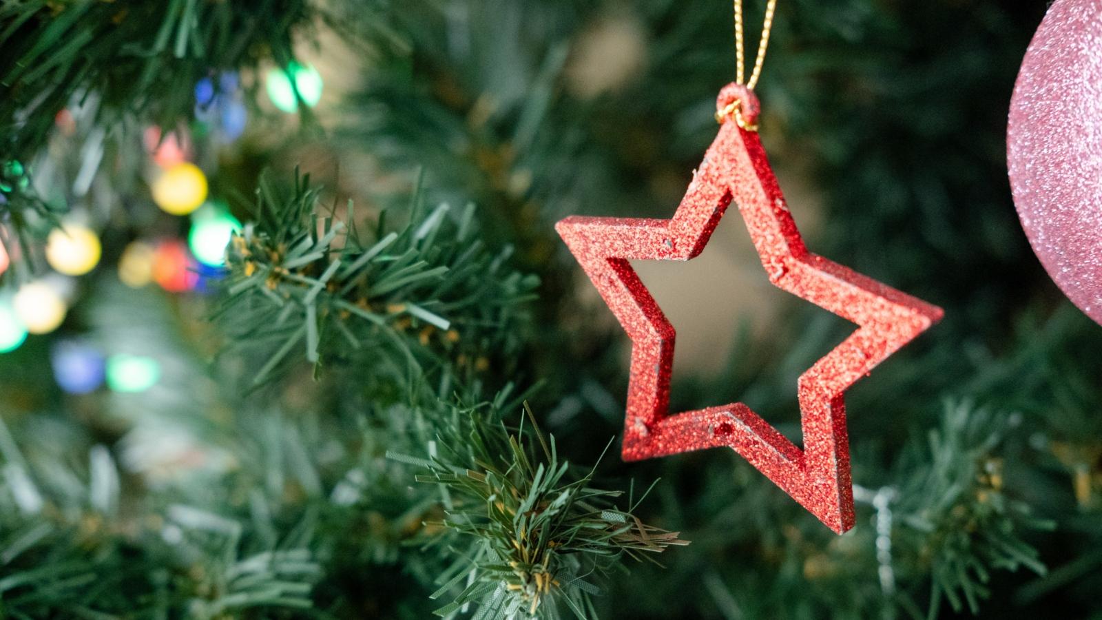 wooden Christmas tree toy in the shape of a star hanging on a branch, close-up