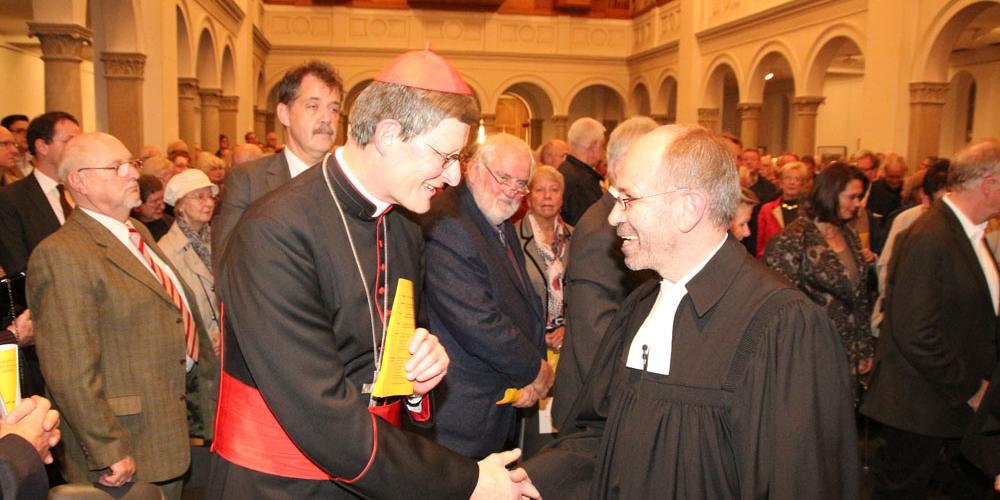 Kardinal Woelki und Präses Manfred Rekowski begrüßen sich in der Kölner Trinitatiskirche