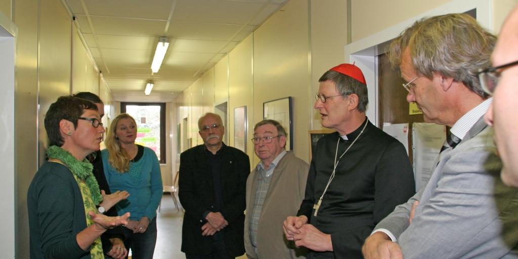 Kardinal zu Besuch im Flüchtlingsheim, im Gespräch mit Mitarbeietnden