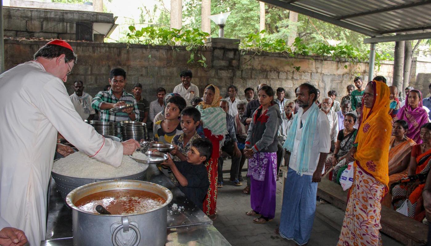 Bei einer Essensausgabe für Bedürftige in Dharmaram segnet Kardinal Woelki die Speisen und hilft anschließend beim Verteilen.