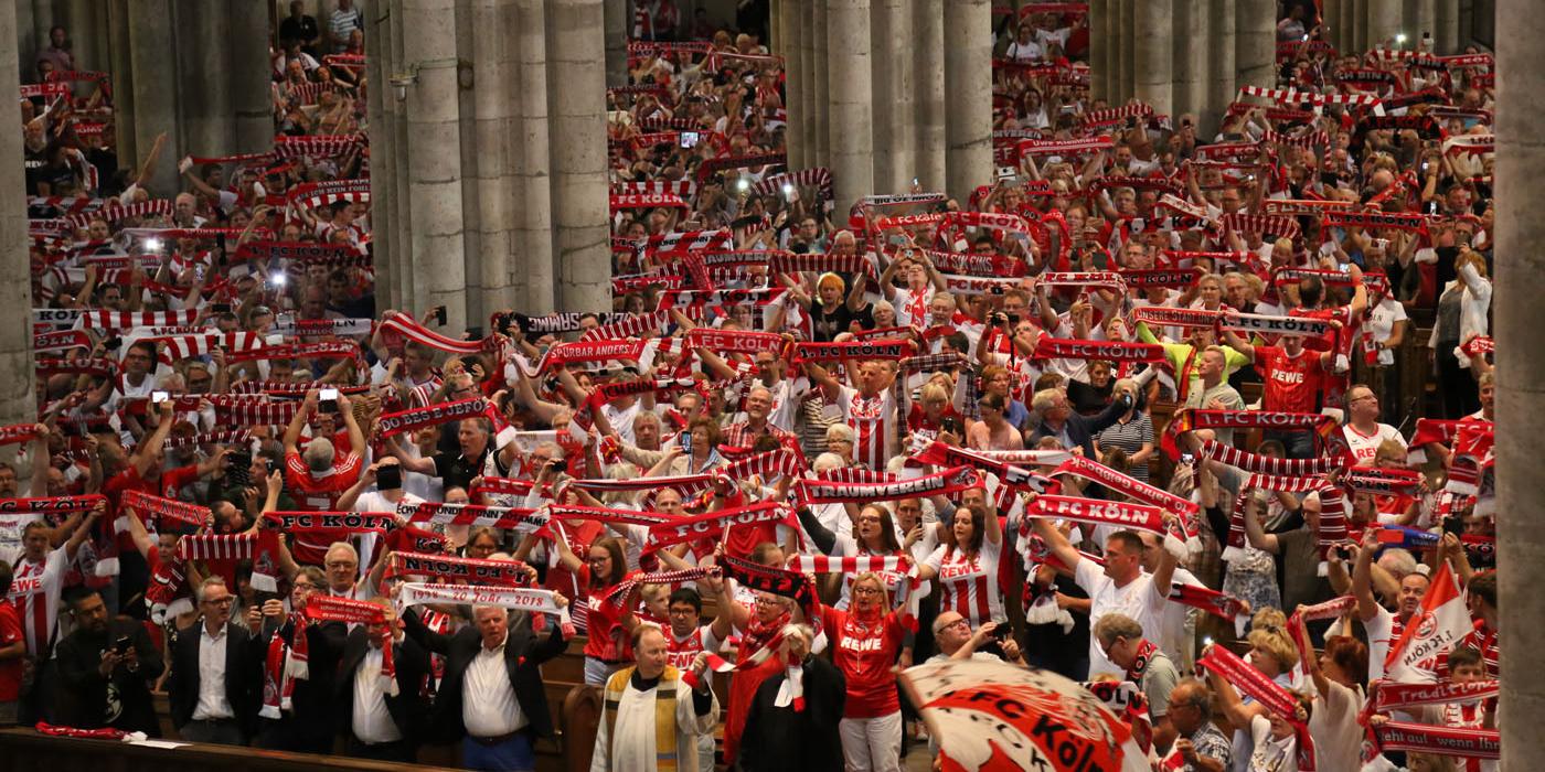 Dom- und Stadtdechant Robert Kleine und Superintendent Markus Zimmermann telen sich einen FC-Schal (vorne) und feiern mit Tausenden die Fanandacht im Kölner Dom.