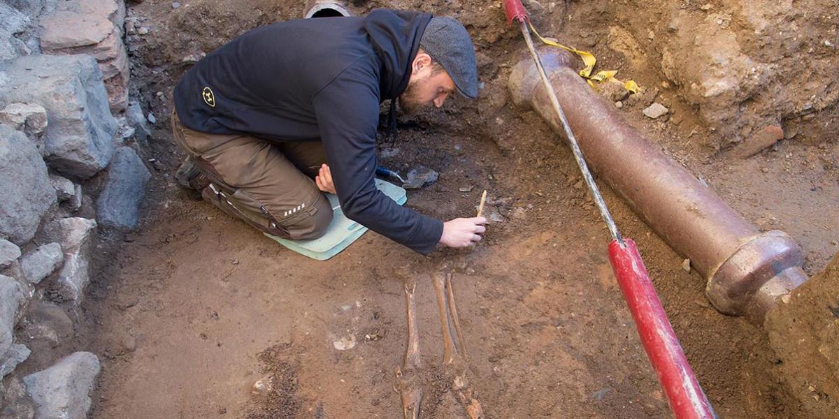 Im Kreuzgang wurden alte Gräber freigelegt. Ein Archäologe arbeitet mit einem Pinsel an den fragilen Stellen eines Skeletts.