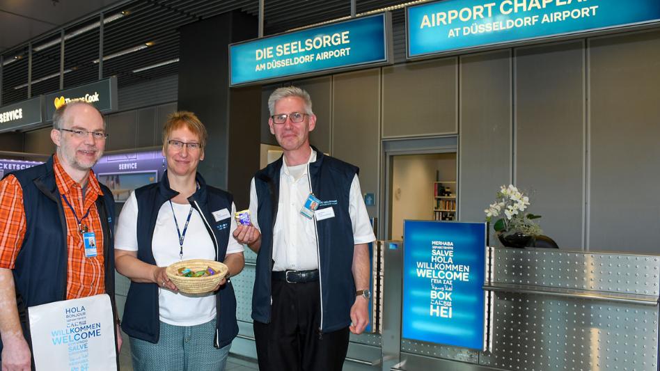 Der Schalter der Flughafenseelsorge in Terminal A, Abflugebene ist gut erkennbar an dem himmelblauen Logo.. Auf dem Bild (v.l.n.r.) sind Pastoralreferent Johannes Westerdick, Diplom-Sozialpädagogin Ute Clevers und der ehrenamtliche Mitarbeiter Jan-Georg Simon.