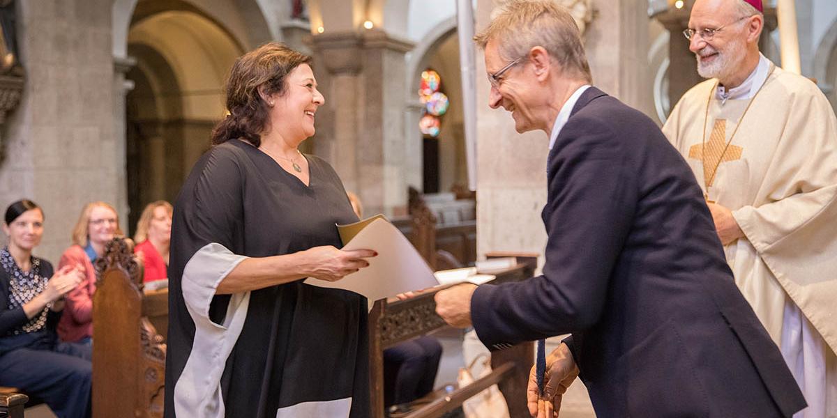 Diözesan-Caritasdirektor Dr. Frank Johannes Hensel (Mitte) übergibt einer Integrationsbeauftragten ihre Urkunde.