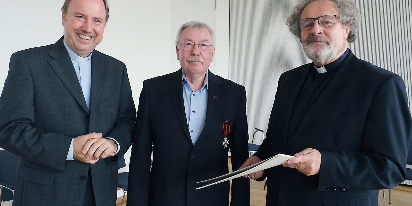 Weihbischof Rolf Steinhäuser und Stadtdechant Robert Kleine überreichen den Silvesterorden an Günter Kühler