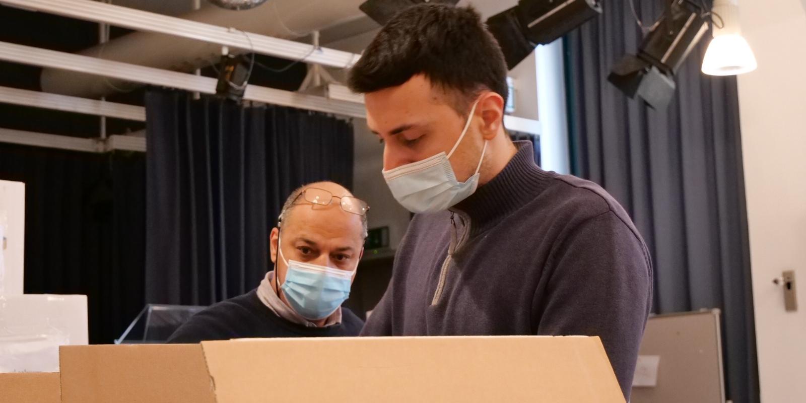 Ahmad S. und sein Sohn helfen beim Sortieren von Sachspenden.