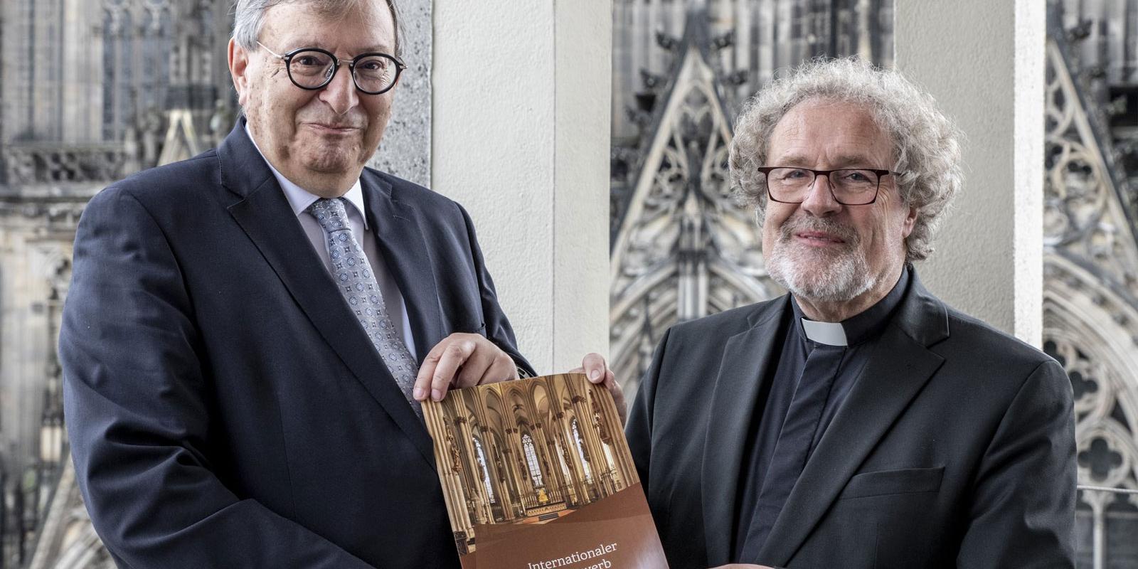 Abraham Lehrer (links) und Weihbischof Rolf Steinhäuser (rechts) präsentieren die Ausschreibung des Internationalen Kunstwettbewerbs.