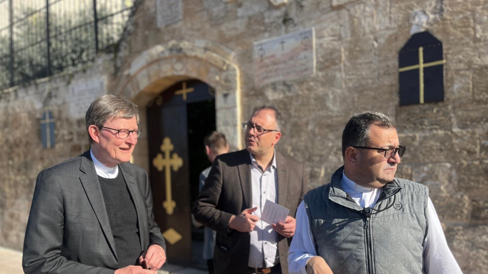 Ein Foto zeigt Kardinal Woelki vor der Kirche einer Gemeinde in Burqin.