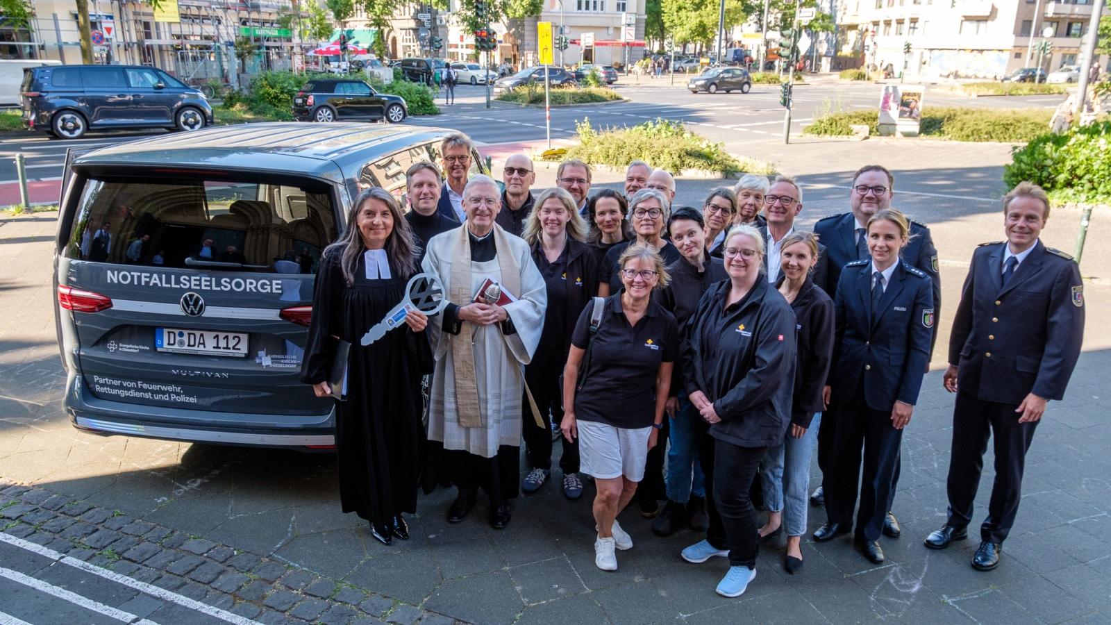 Das Foto zeigt die eine Gruppe Personen neben einem Kleinbus.