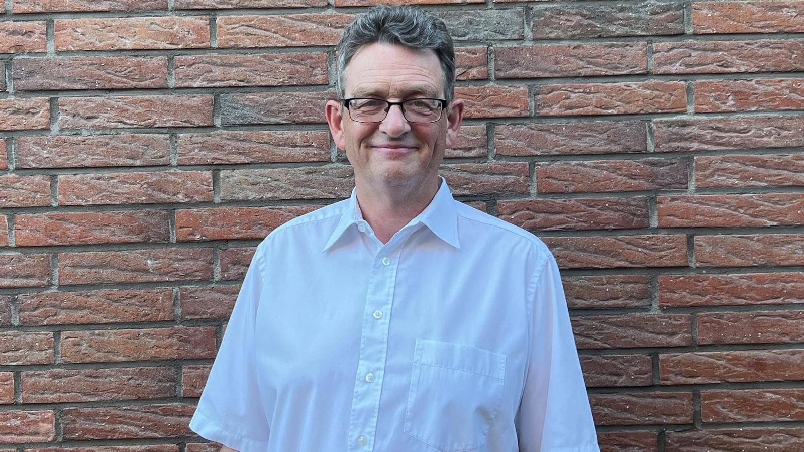 Ein Foto von Diakon Gregor Hergarten vor einer Mauer.
