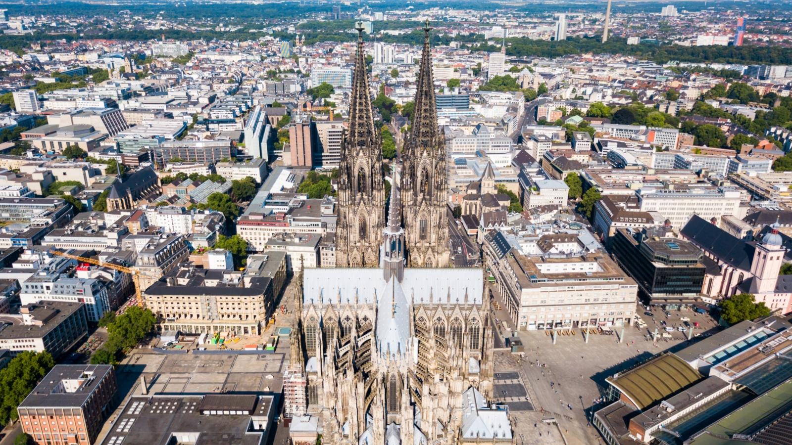 Ein Foto zeigt eine Luftaufnahme des Kölner Doms mit der Innenstadt im Hintergrund.