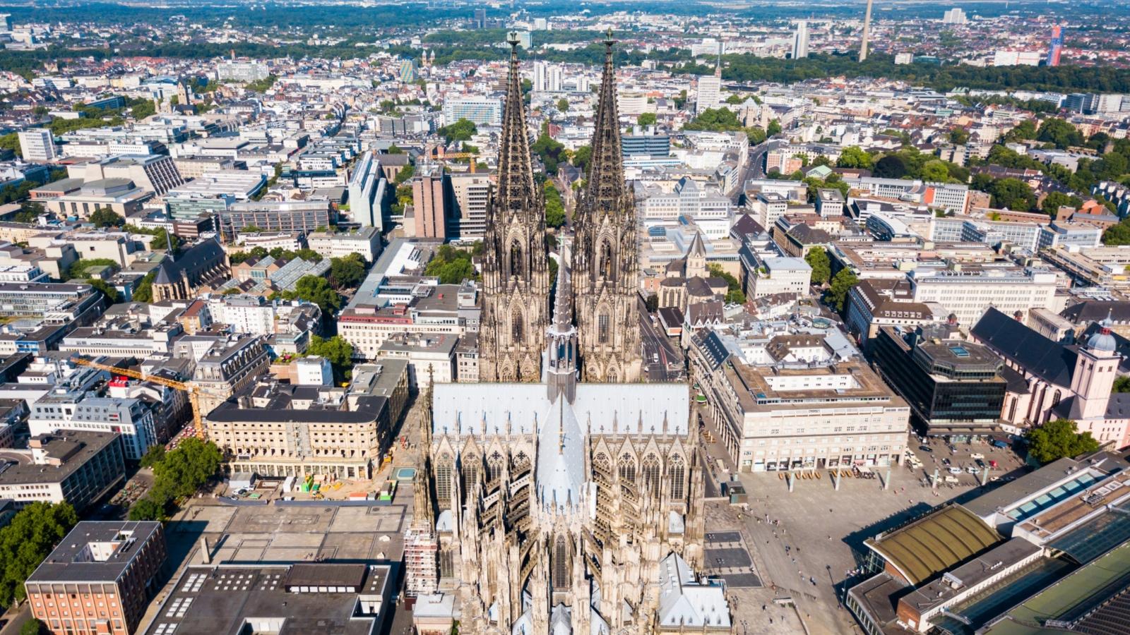 Ein Foto zeigt eine Luftaufnahme des Kölner Doms mit der Innenstadt im Hintergrund.