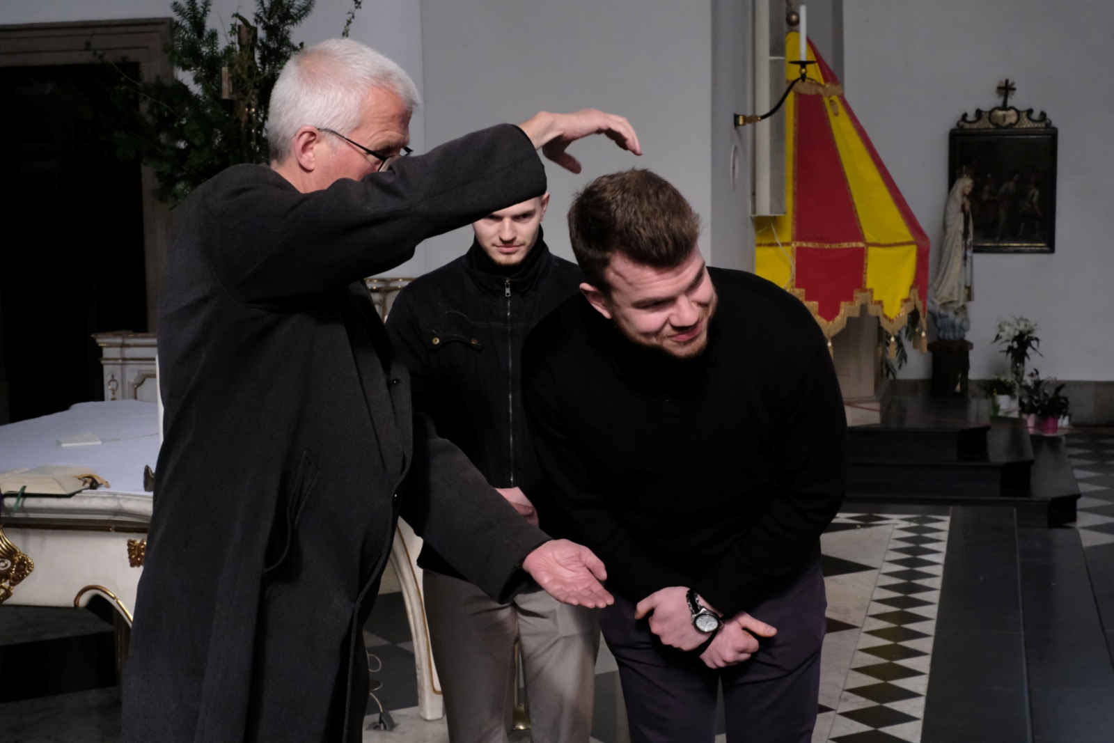 Ein Foto zeigt Pfarrer Kurth mit zwei Männern in einer Kirche.