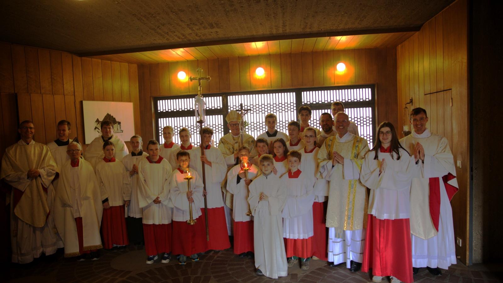 Gruppenbild mit Kardinal Woelki, Abbés der Gemeinschaft Saint Martin und Messdienern. Bei der Familienwallfahrt an Christi Himmelfahrt (14.05.2026) feierten große und kleine Gläubige gemeinsam mit dem Kölner Erzbischof. Dieser bedankte sich für den Einsatz vor Ort. In seiner Predigt riet er Christen aber auch zu mehr Überzeugung.