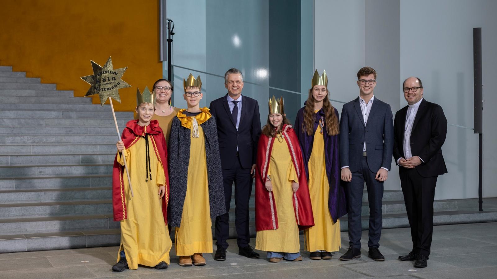 Die Sternsingerinnen und Sternsinger Kim (14), Julia (11), Julius (14) und Mirek (12) sowie Begleiter Maximilian Zygmunt aus der Pfarrgemeinde St. Lambertus in Mettmann vertraten das Erzbistum Köln am Dienstagnachmittag beim Sternsingerempfang zur 68. Aktion Dreikönigssingen im Bundeskanzleramt. Zum Gruppenfoto mit Thorsten Frei, Chef des Bundeskanzleramts, stellten sie sich gemeinsam auf mit Pfarrer Dirk Bingener, Präsident des Kindermissionswerks ‚Die Sternsinger‘, und Daniela Hottenbacher, Bundesvorsitzende des Bundes der Deutschen Katholischen Jugend (BDKJ).