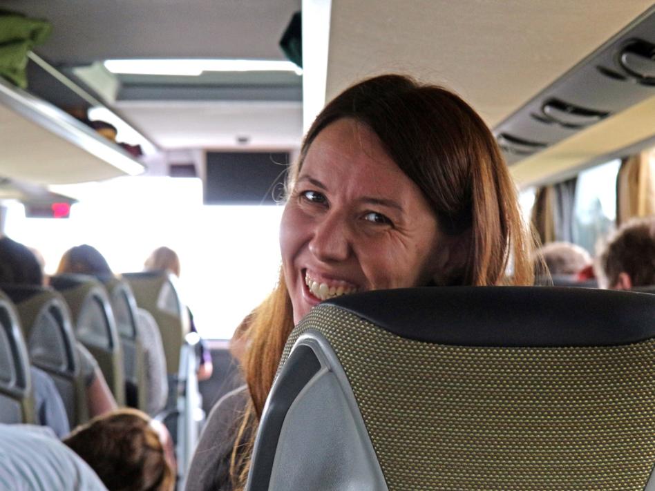 Eine Frau sitzt im Reisebuch, schaut lächelnd nach hinten in die Kamera