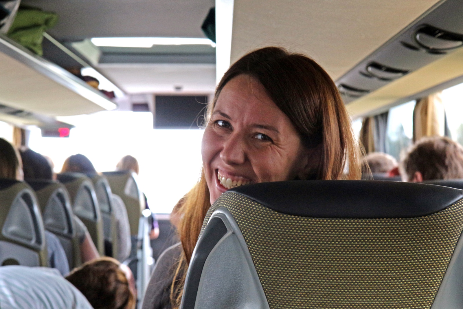 Eine Frau sitzt im Reisebuch, schaut lächelnd nach hinten in die Kamera