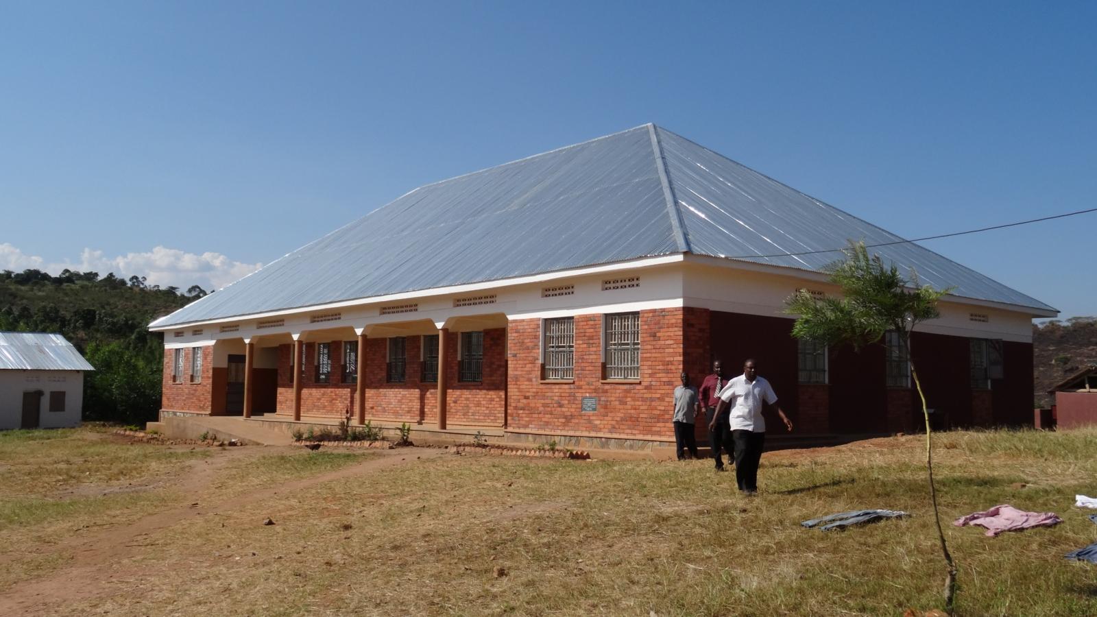 Das Bild zeigt ein Schulgebäude. Davor ist ein Mann zu sehen.