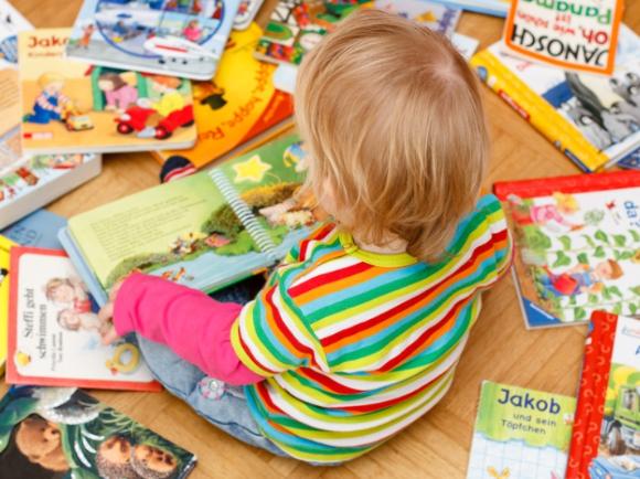 Kind sitzt zwischen Bilderbüchern