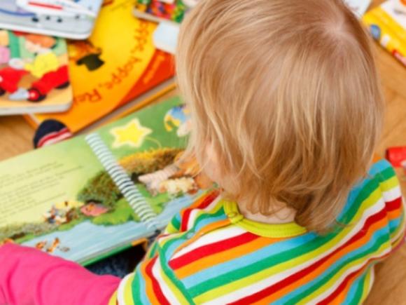 Kind sitzt zwischen Bilderbüchern