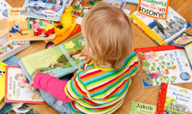 Kind sitzt zwischen Bilderbüchern