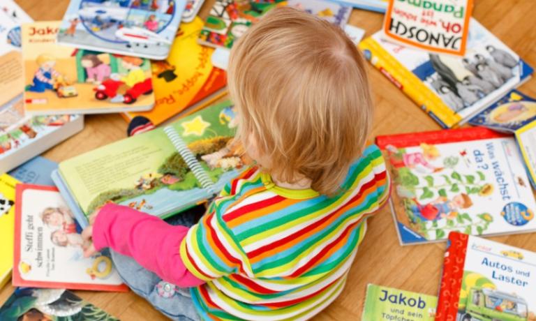 Kind sitzt zwischen Bilderbüchern