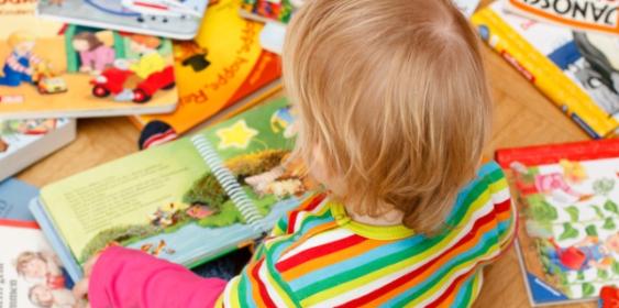 Kind sitzt zwischen Bilderbüchern