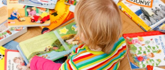 Kind sitzt zwischen Bilderbüchern