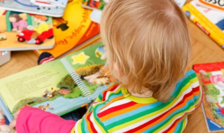 Kind sitzt zwischen Bilderbüchern
