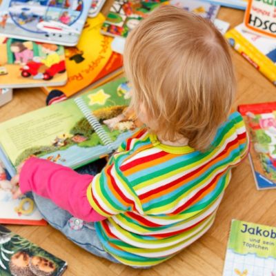 Kind sitzt zwischen Bilderbüchern