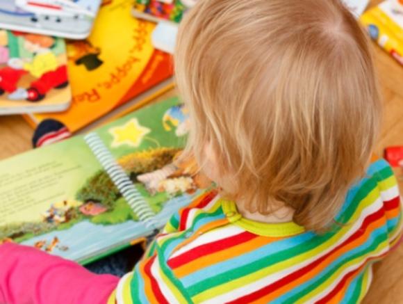 Kind sitzt zwischen Bilderbüchern