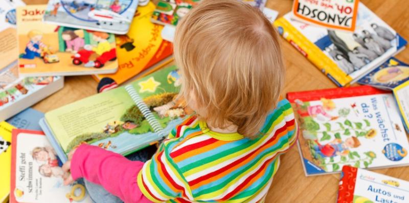 Kind sitzt zwischen Bilderbüchern