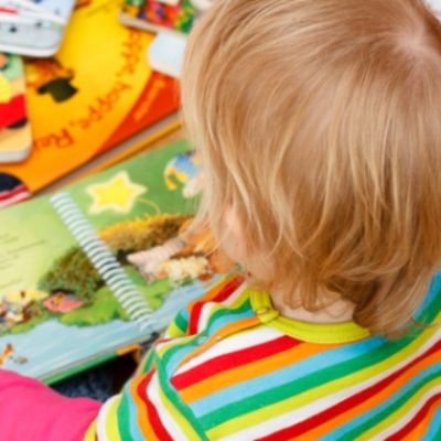 Kind sitzt zwischen Bilderbüchern