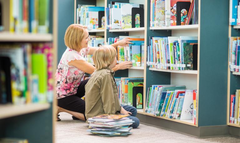 Frau mit Kind am Bücherregal