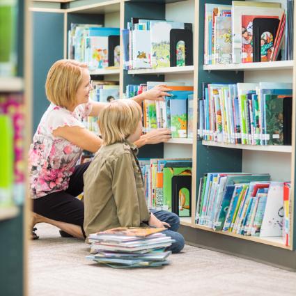 Frau mit Kind am Bücherregal