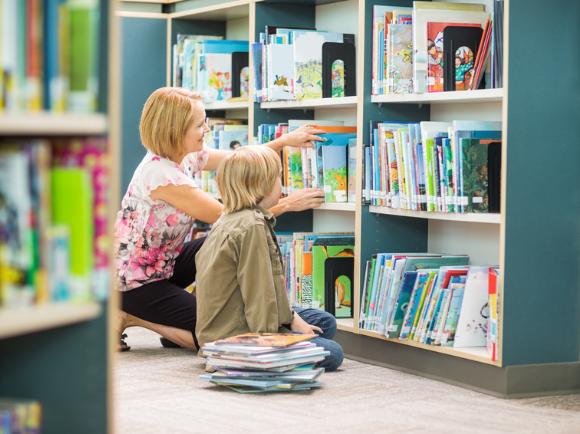 Frau mit Kind am Bücherregal