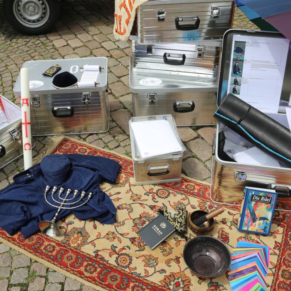 Teppich auf dem diverse Materialien liegen: Osterkerze, Klangschale, Bibel, Koran, etc.