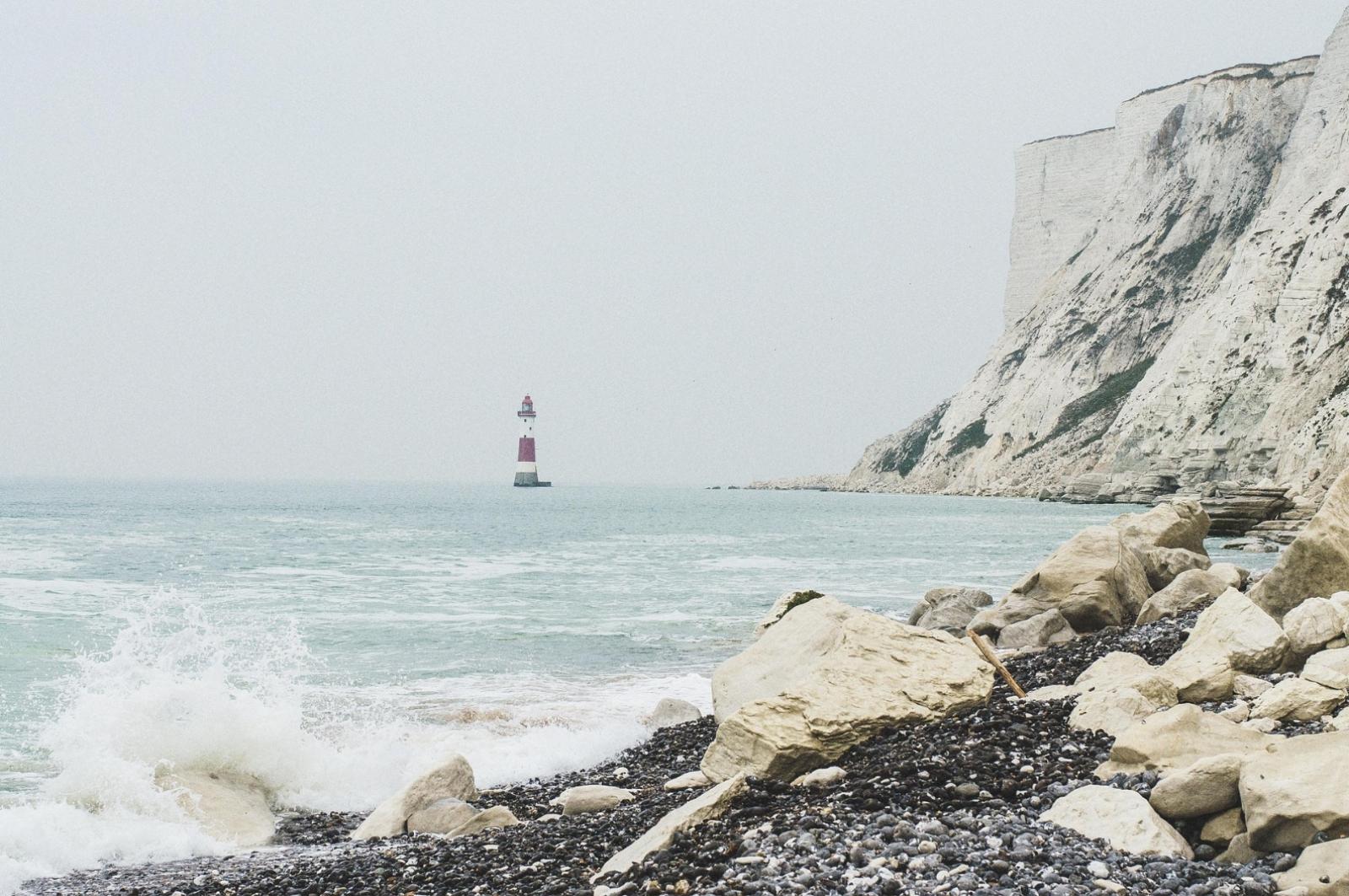 Leuchtturm im Meer an einer schroffen Küstenlandschaft