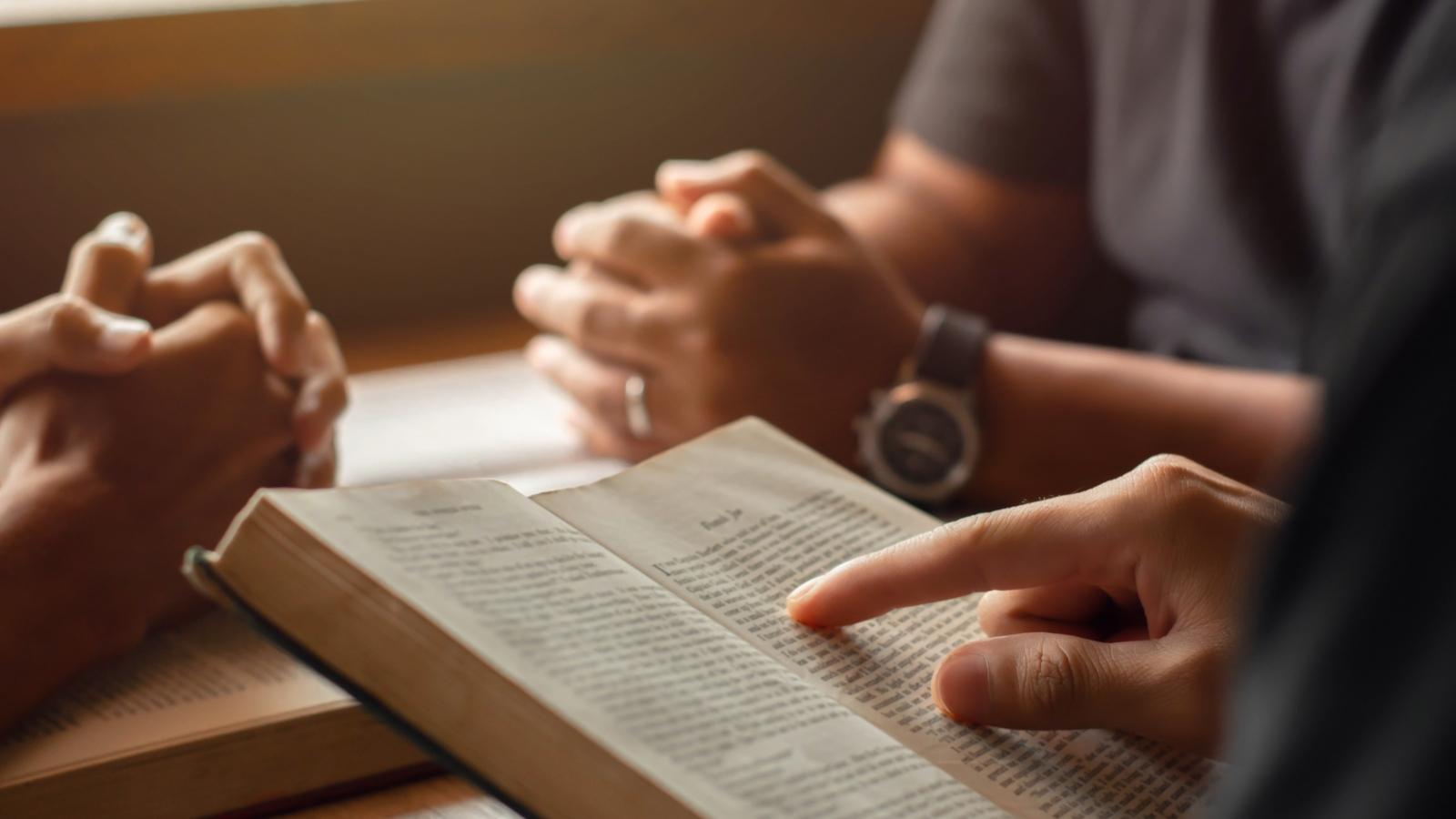 young man reading bible with friends who are praying to God Join the cell group at the church. A small group of Christians or concepts in a church at a church.