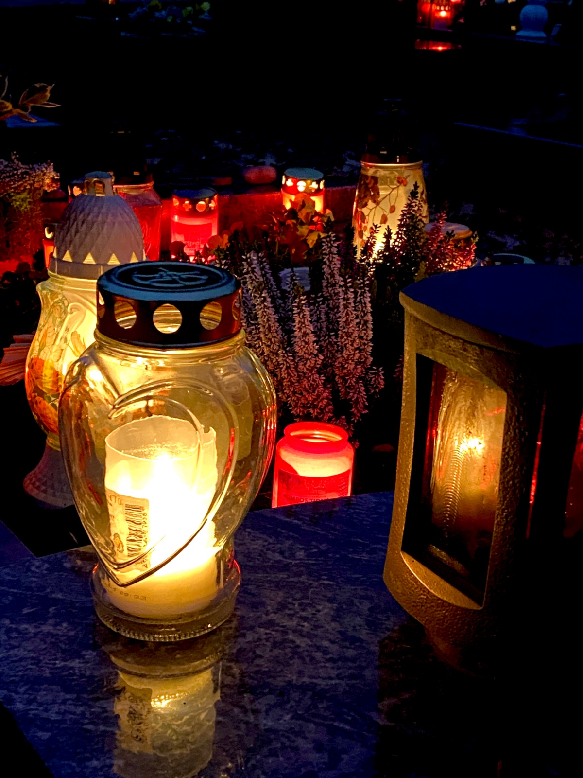 Foto von Grablichtern auf dem Friedhof im Dunkeln.