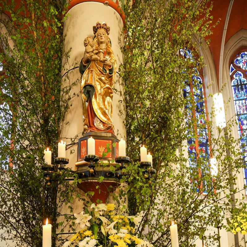 Mit Blumen und Birkenzweigen geschmückter Maialtar in der Sankt Barbara Kirche in Bonn-Ippendorf.