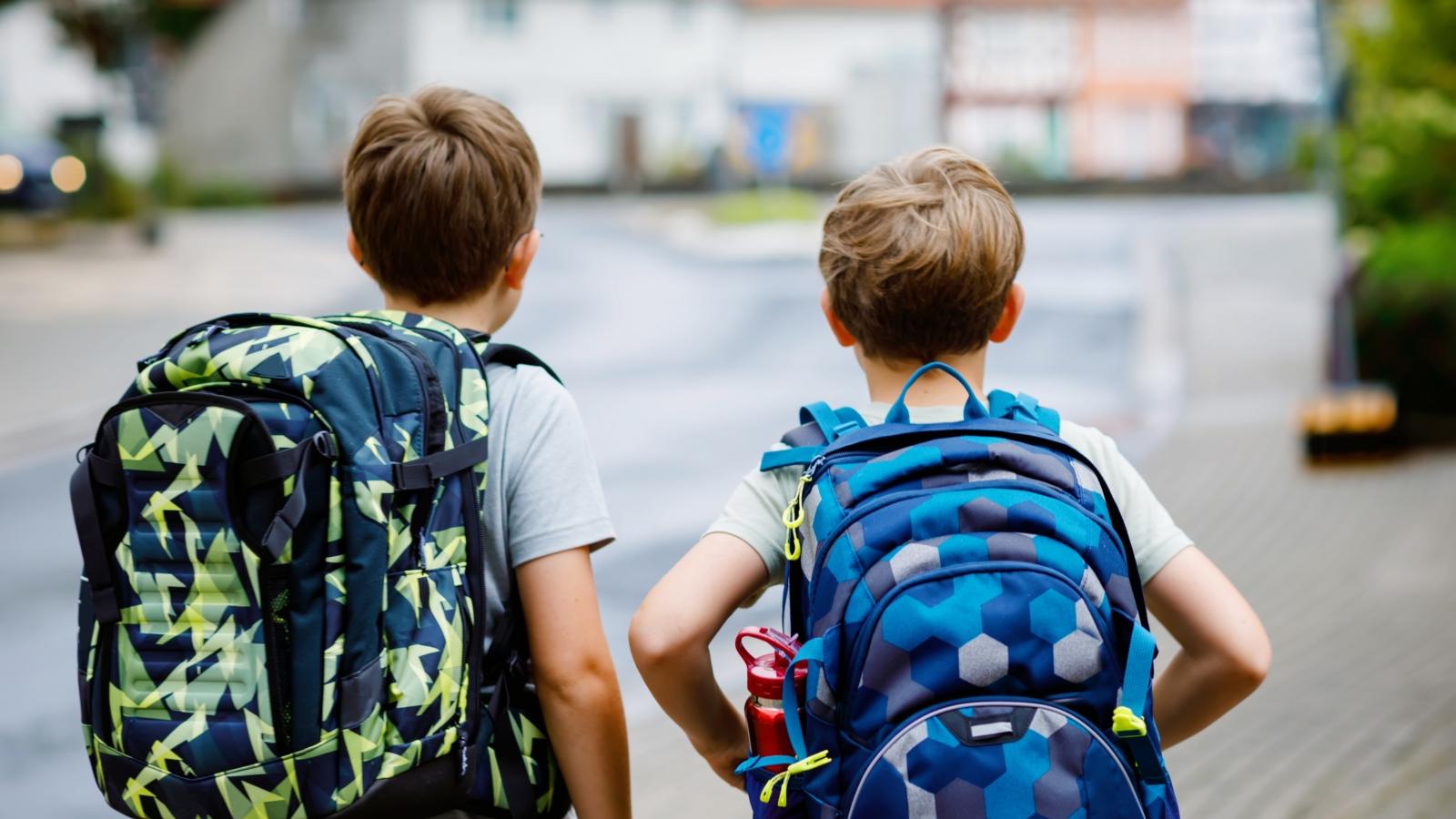 Ein Foto zeigt zwei Kinder mit Schulranzen auf dem Rücken.