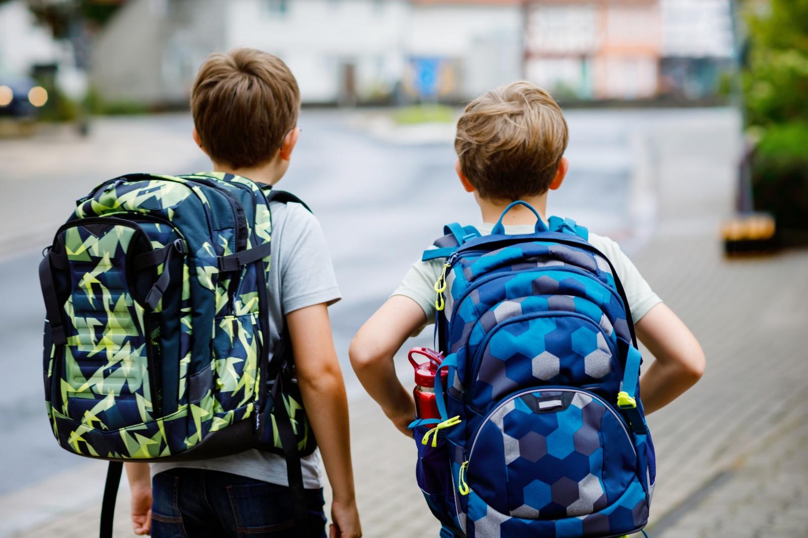 Ein Foto zeigt zwei Kinder mit Schulranzen auf dem Rücken.