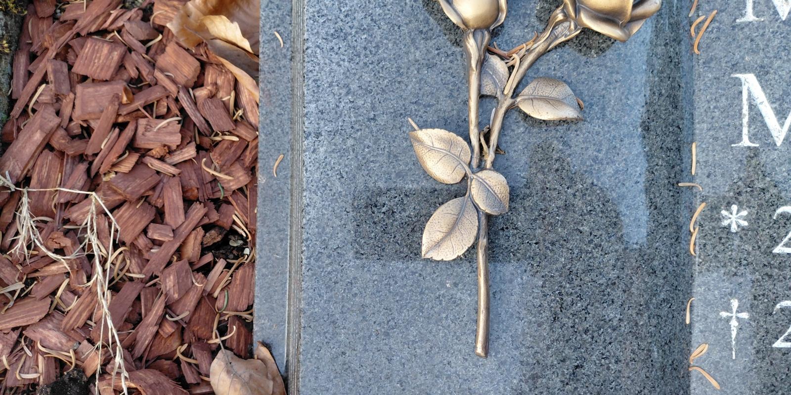 Bild von einem Grabstein auf dem eine Rose abgebildet ist