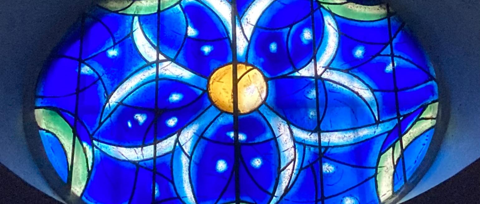Das Bild zeigt ein blaues Kirchenfenster aus der Kirche St. Stephan