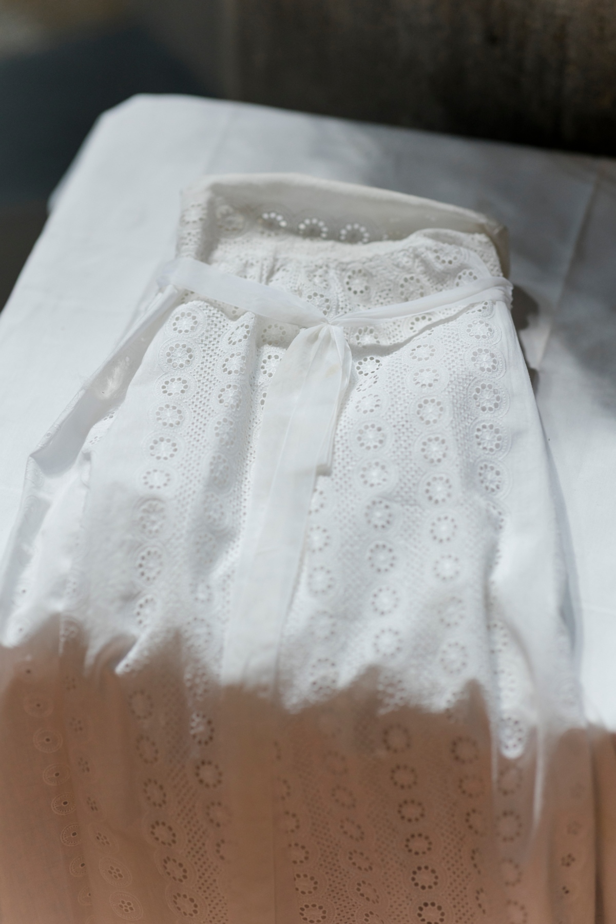 Weißes Taufkleid liegt auf einem Tisch.