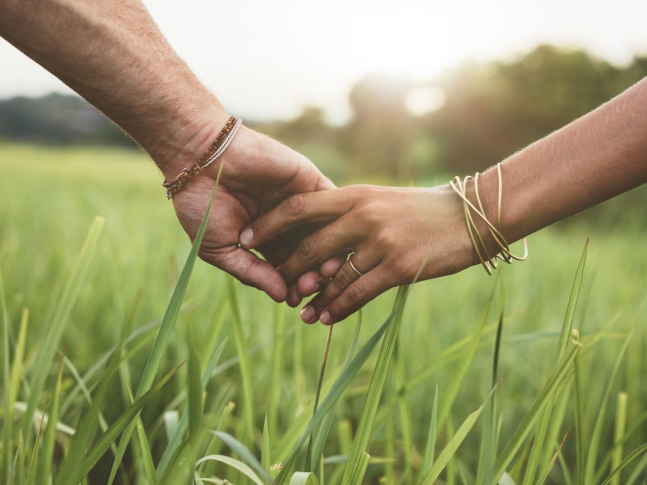 Romantic couple holding hands in a field