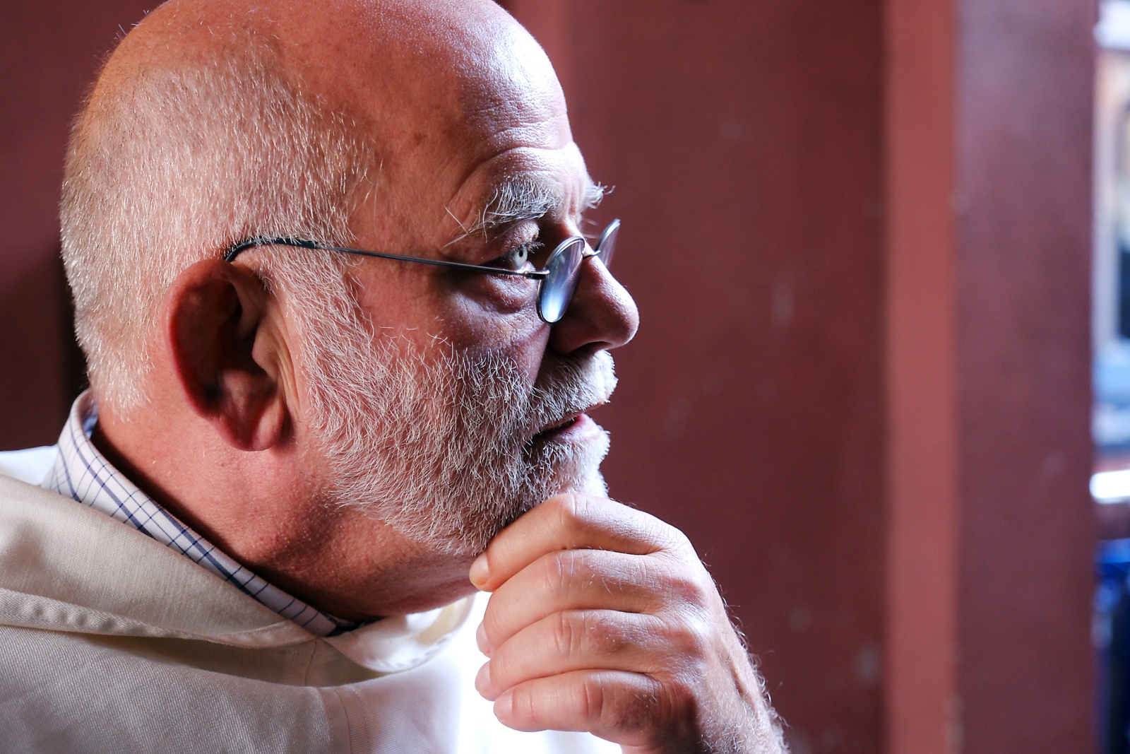 Ein Foto zeigt einen älteren Mann von der rechten Seite. Mit einer Hand hält er das Kinn.